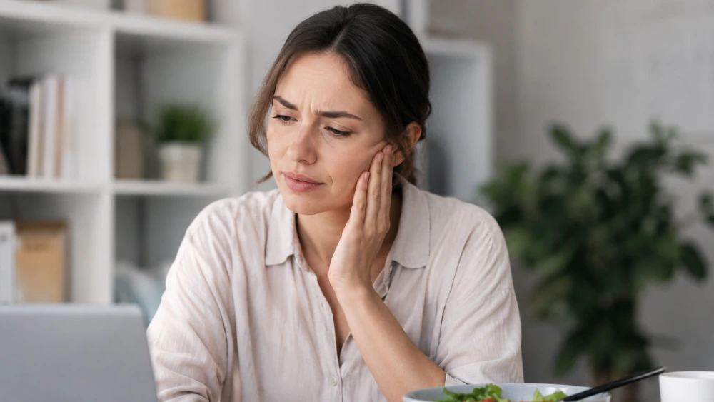 A person holding their jaw near the ear, experiencing discomfort from TMJ dysfunction and jaw clicking.